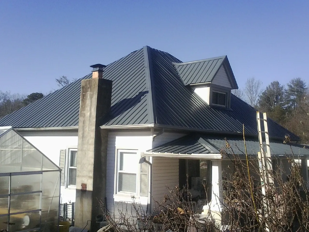 Dark blue standing seam metal roof on a white farmhouse with dormer — Slate & Tile Roof Repair by Roofing Brothers in Rowley