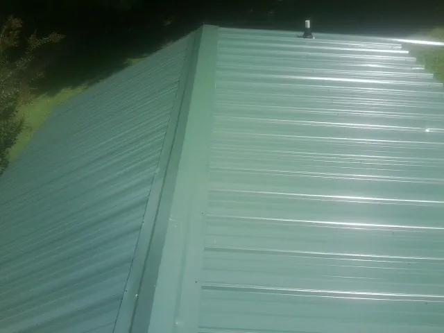 New green metal panels meeting at the ridge of a roof — Flat Roof Repair work by our crew in Rowley