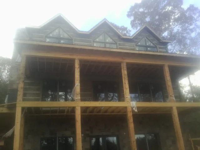 Dormers and porch framing on a large log home under construction — Roof Coating work by our crew in Rowley