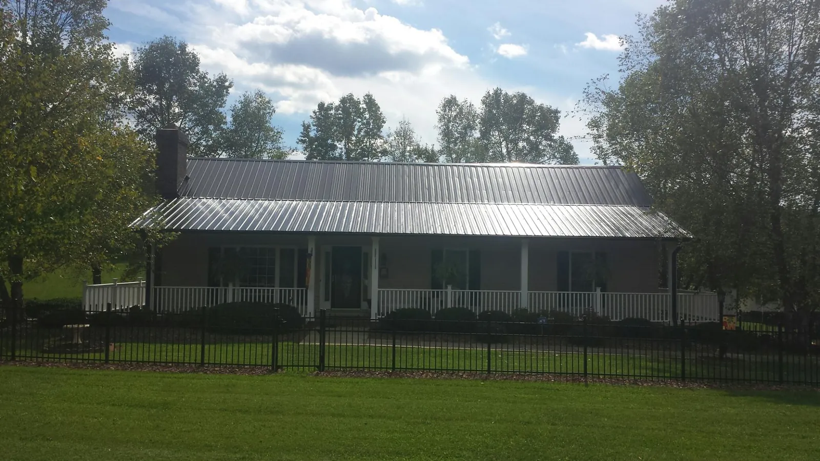 Gray metal roof on a brick ranch with a full width front porch — Gutter Guard Installation work by our crew in Rowley