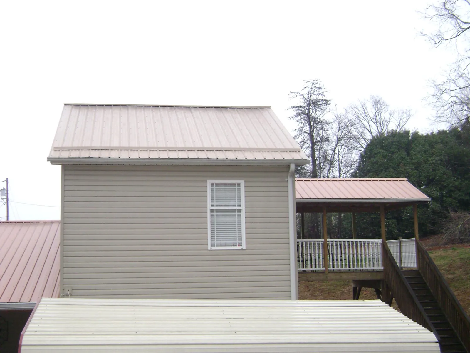 Tan metal roofs on a two story addition and attached porch, from a Roof Replacement job in Rowley