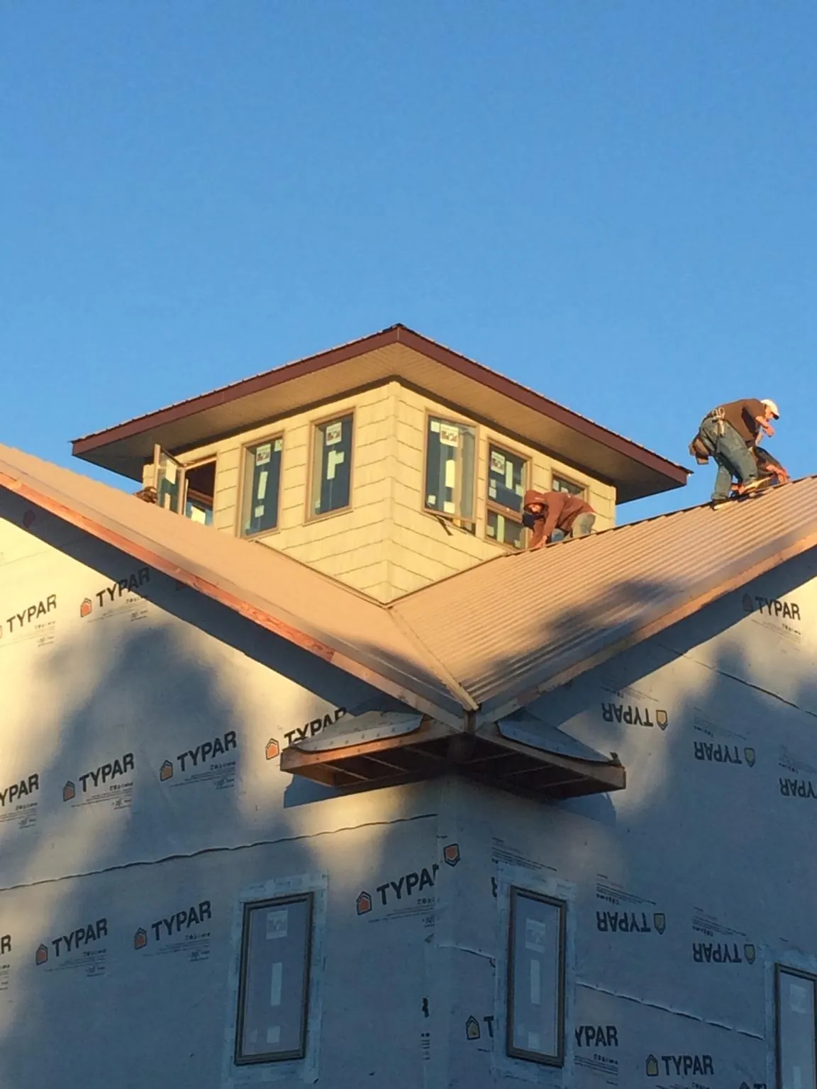 Roofers working around a rooftop cupola on a new metal roof at sunset — Roof Waterproofing in Rowley by Roofing Brothers
